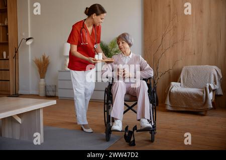 Dame senior recevant des pilules d'une travailleuse de santé à la maison de retraite Banque D'Images