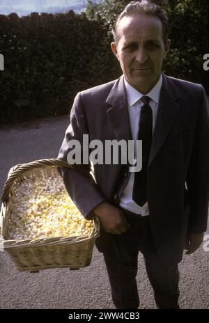 Forestier de la forêt de Dean Keith Creswick, avec un panier de pain et de fromage qui est jeté du mur de l'église après le chant d'soirée le dimanche de Whit. Festival annuel de lancement de fromage de pain St Briavels Gloucestershire Angleterre. ANNÉES 1970 ROYAUME-UNI HOMER SYKES Banque D'Images