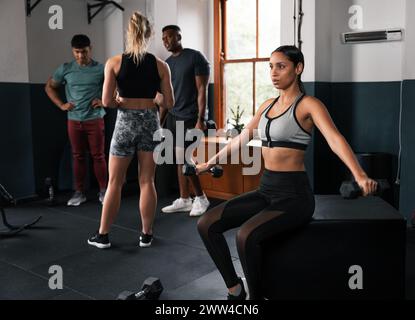 Femme sur le banc de gymnastique tenant l'haltère, se concentrant sur l'exercice musculaire de jambe Banque D'Images