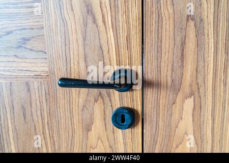 Élégance dans le détail. Gros plan de la poignée de porte noire sur fond en bois brun. Banque D'Images