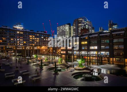 Londres, Royaume-Uni : vue nocturne du domaine Barbican dans la ville de Londres avec lac et fontaines. Banque D'Images