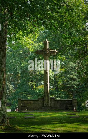 2023 - cimetière de Lowell - Lowell, ma. Énormes monuments de croix religieuse avec des lumières brumeuses drapant à travers la scène entouré d'herbe verte riche et t Banque D'Images