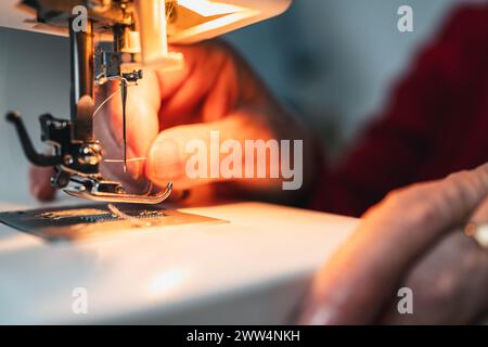 détail des doigts enfilant l'aiguille de machine à coudre Banque D'Images