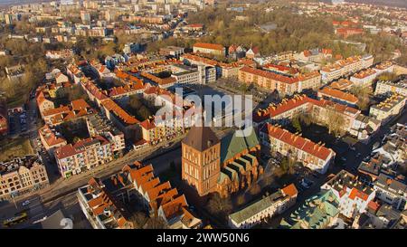 Un drone capture le centre-ville de Koszalin baigné de lumière dorée, avec la cathédrale, Victory Street et l'hôtel de ville. Banque D'Images