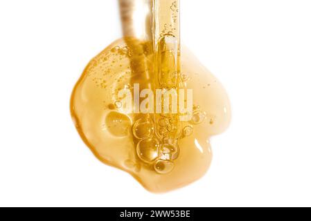 Pipette compte-gouttes et échantillon de sérum doré ou de gel de rétinol isolé sur fond blanc. Soin de la peau avec huile ou peptide. Échantillon de texture de cosmétique Banque D'Images