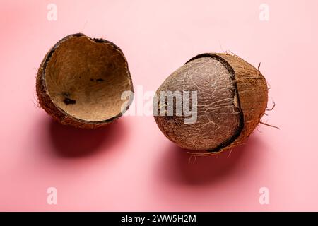 Deux noix de coco sont représentées, dont une ouverte. L'autre est fermé. Les noix de coco sont sur un fond rose Banque D'Images