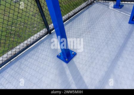 Vue de la dugout typique de baseball de lycée non descript avec sol en béton, clôture à maillons de chaîne et abat-jour bleu sur le toit. Banque D'Images