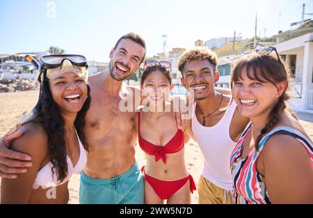 Portrait joyeux d'un groupe d'amis divers sur la plage s'amusant à poser et à regarder la caméra Banque D'Images