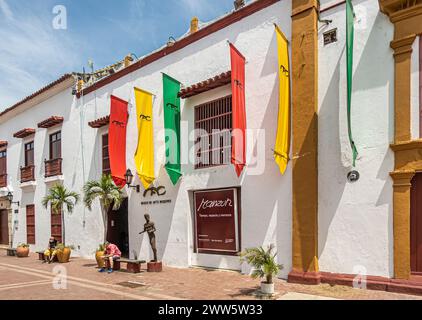 Carthagène, Colombie - 25 juillet 2023 : Plaza del Parque o de Armas, place. Musée d'art moderne façade blanche avec drapeaux colorés. Petite figure humaine statu Banque D'Images