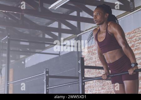 Une femme afro-américaine d'âge moyen forte et en forme fait des pull-ups avec un espace de copie Banque D'Images