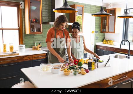 Un couple diversifié prépare un repas ensemble dans une cuisine moderne Banque D'Images