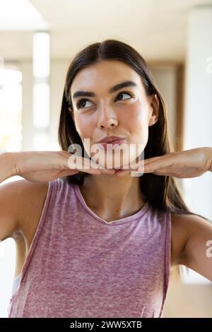 Une jeune femme brune caucasienne pose de manière ludique à la maison Banque D'Images