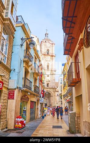 MALAGA, ESPAGNE - 28 septembre 2019 : L'étroite Calle San Juan avec de nombreux petits magasins et une vue sur le grand clocher en pierre de l'église San Juan, le 28 septembre Banque D'Images