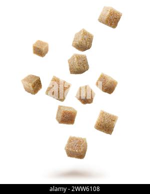 Cubes de sucre de canne brun tombant sur fond blanc Banque D'Images