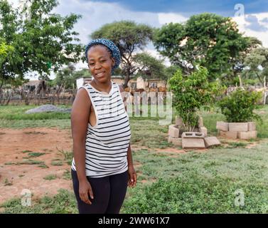 jeune femme africaine, vaches dans le kraal en arrière-plan, vie villageoise en afrique du sud Banque D'Images