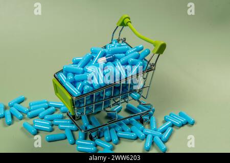 Pilules bleues dans un panier sur un fond vert. Concept d'achat de médicaments. Pilules bleues dans un panier sur un fond vert. Concept d'achat Banque D'Images