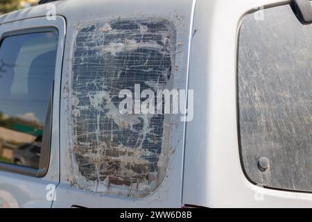Fenêtre de quart de SUV argenté cassée et recouverte de plusieurs couches de ruban adhésif transparent, fixation temporelle rapide bon marché Banque D'Images
