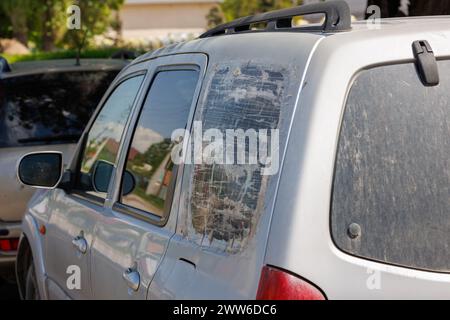 Fenêtre de quart de SUV argenté cassée et recouverte de plusieurs couches de ruban adhésif transparent, fixation temporelle rapide bon marché Banque D'Images