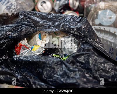 Déchets ménagers dans un sac en plastique sur une bande transporteuse dans une installation de traitement Banque D'Images