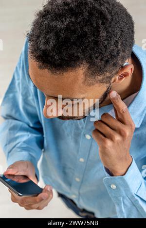 Jeune homme ajustant l'intensité du volume de l'aide au coeur avec le smartphone. Banque D'Images