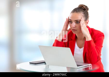 Femme face à son ordinateur serrant sa tête avec ses doigts. Banque D'Images