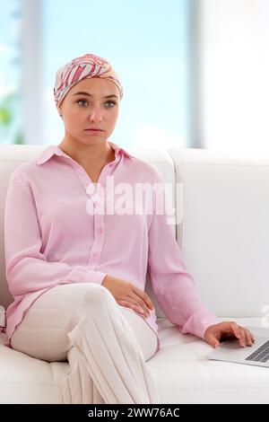 Femme portant un foulard assis sur le canapé, regardant dans l'espace. Banque D'Images