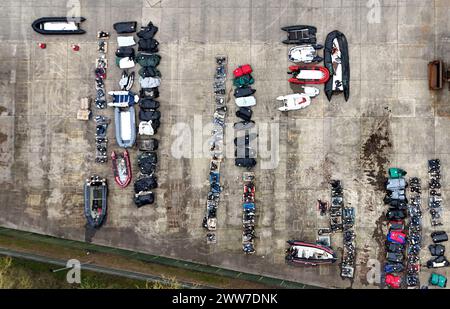 Une vue de petits bateaux et moteurs utilisés pour traverser la Manche par des personnes considérées comme des migrants dans un entrepôt à Douvres, Kent. Date de la photo : vendredi 22 mars 2024. Banque D'Images