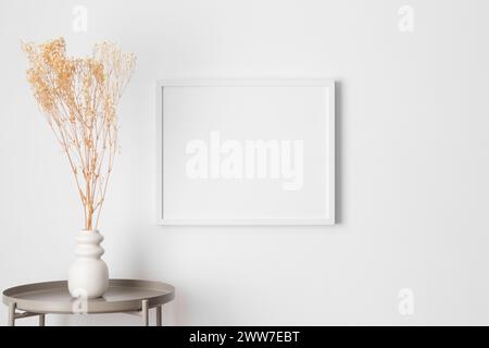 Maquette de cadre blanc sur le mur avec une décoration gypsophila. Banque D'Images