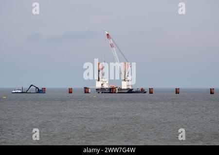 PRODUCTION - 14 mars 2024, basse-Saxe, Wilhelmshaven : une grue flottante est utilisée pendant les travaux de construction d'une jetée nécessaire pour un deuxième terminal GNL à Wilhelmshaven. Le nouveau terminal est en construction dans la baie de Jade entre le premier terminal GNL et le quai de la raffinerie de Voslapper Groden. Photo : Hauke-Christian Dittrich/dpa Banque D'Images