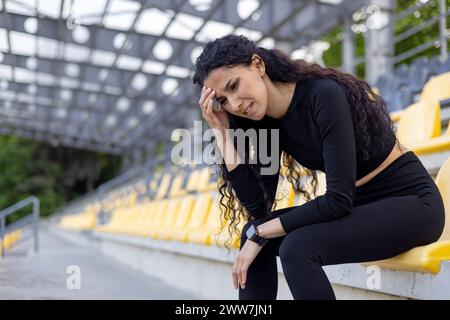 Une femme athlétique en vêtements de sport prenant un repos sur les sièges jaunes du stade après l'exercice. Concept de fitness et de mode de vie sain. Banque D'Images