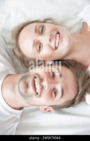 Smiling Couple Lying on Bed face à des directions opposées Banque D'Images