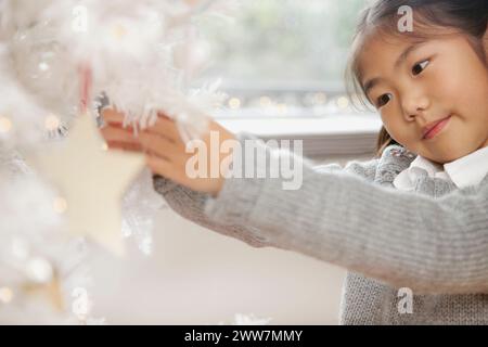 Close up of Young Girl Decorating Christmas Tree Banque D'Images