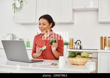 nutritionniste afro-américain tenant avocat et suppléments tout en donnant des conseils diététiques en ligne Banque D'Images