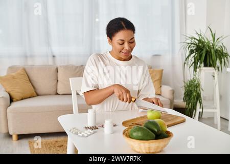 happy african american nutritionnist compare les suppléments avec les fruits pour une alimentation saine à la maison Banque D'Images