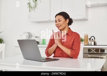 nutritionniste féminine souriante offrant une consultation en ligne tout en travaillant à distance depuis sa cuisine Banque D'Images