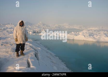 Un chasseur de subsistance Inupiaq se tient sur la banquise rugueuse, après avoir observé des conditions instables de glace de mer non loin du rivage, la mer des Tchouktches Alaska Banque D'Images