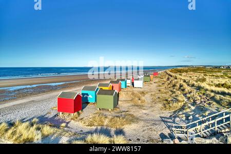 Findhorn Moray Coast Scotland rangée de cabanes de plage colorées surplombant la plage de sable et la mer bleue Banque D'Images