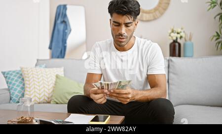 Beau jeune homme comptant des billets de zloty polonais à la maison sur un canapé confortable, style de vie décontracté. Banque D'Images