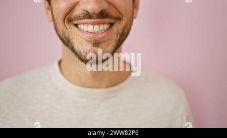 Gros plan d'un jeune homme hispanique souriant avec une barbe sur un fond rose, dépeignant positivité et chaleur. Banque D'Images