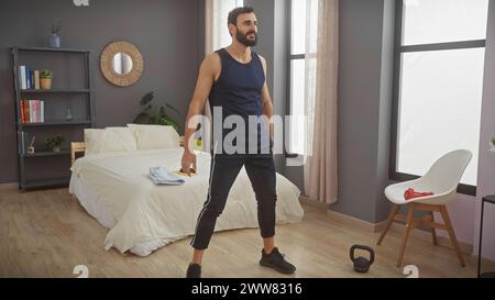 L'homme barbu dans la chambre se tient en toute confiance, affichant un style de vie sain et un design intérieur moderne. Banque D'Images