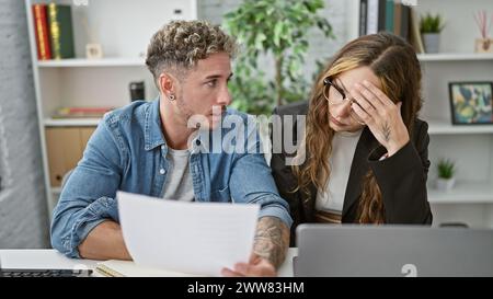 L'homme et la femme concernés avec des papiers discutent des questions de travail dans un cadre de bureau moderne. Banque D'Images