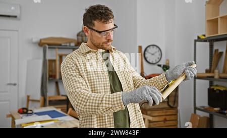 Un artisan concentré mesure le bois dans un atelier bien équipé. Banque D'Images