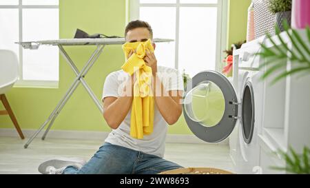 Beau jeune homme sentant le linge frais dans un cadre intérieur lumineux Banque D'Images