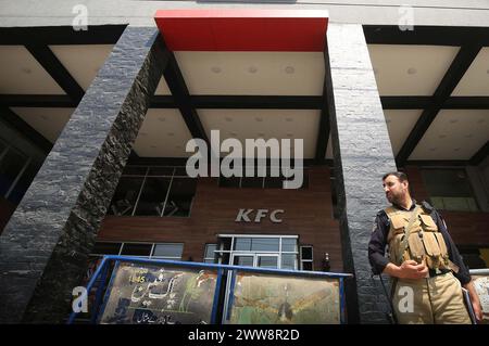 Les policiers sont en état d'alerte pour éviter un incident fâcheux devant la succursale du restaurant Kentucky Fried Chicken (KFC) après sa fermeture temporaire suite à une manifestation de solidarité avec le peuple palestinien, à Peshawar le vendredi 22 mars 2024. Banque D'Images