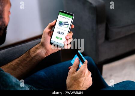 Homme tenant une carte de crédit et un téléphone portable sur le point de payer un achat en ligne. Banque D'Images