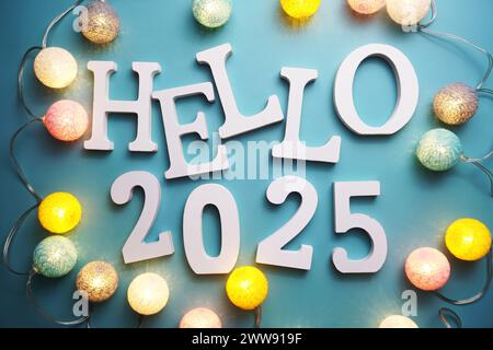 Hello 2025 lettre alphabet avec décoration LED boule de coton sur fond bleu Banque D'Images