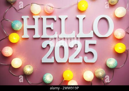 Hello 2025 lettre alphabet avec décoration LED boule de coton sur fond rose Banque D'Images