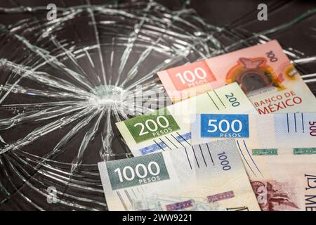 Argent mexicain, problèmes de pesos, affaiblissement de la monnaie mexicaine, Bundle of Mexican money on Broken Glass background, concept financier ou coûts d'assurance Banque D'Images