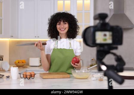 Blogueur alimentaire souriant expliquant quelque chose tout en enregistrant une vidéo dans la cuisine Banque D'Images