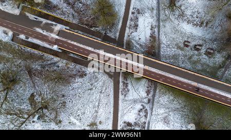Photographie par drone d'une passerelle traversant la rivière de la ville au parc public pendant la journée nuageuse d'hiver Banque D'Images